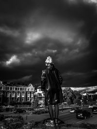 Statue against storm clouds in city