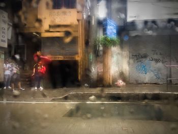 Woman walking by buildings in city at night