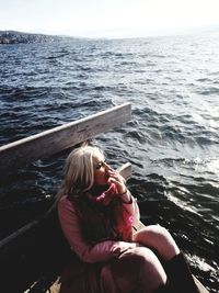 Woman sitting in sea against sky
