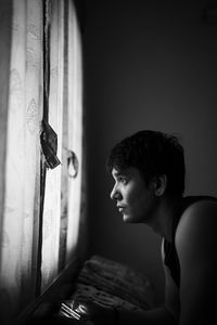 Side view of young man looking away on bed at home