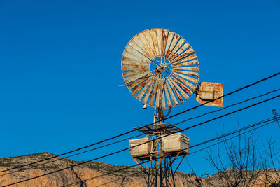 Low angle view of ferris wheel against clear blue sky