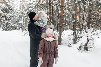 Father with two daughters walking through the winter forest. high quality photo