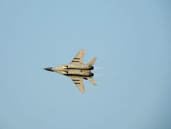 Low angle view of airplane flying against clear blue sky