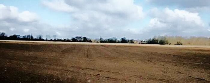 Scenic view of field against cloudy sky