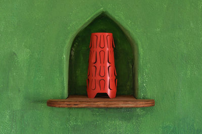 Red lamp on a wooden shelf encased in a green wall of a typical rural house in fuerteventura, 