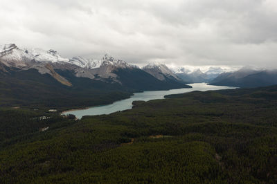 Aerial view of maligne lake on a cloudy autumn day with the mountain peaks full of snow.