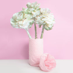 Close-up of pink flower vase on table against wall