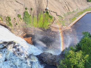 High angle view of water flowing through rocks with rainbow