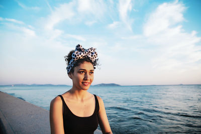 Beautiful woman sitting on retaining wall by sea