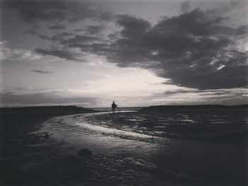 Silhouette man standing on beach against sky during sunset