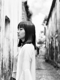 Side view of young woman standing against trees