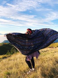 Midsection of woman on field against sky