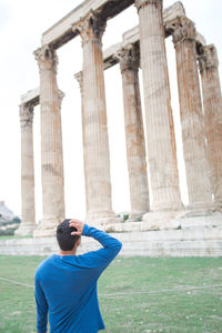 Rear view of man standing by temple of olympian zeus