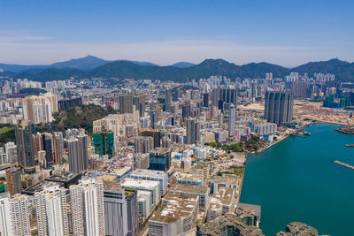 Aerial view of sea and buildings in city against sky