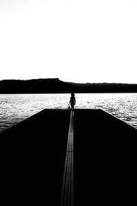 Silhouette person standing on boat against clear sky