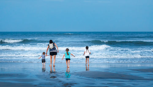 Family memories with mom and three kids enjoying a relaxing walk on the beach