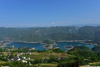 Scenic view of lake and mountains against clear blue sky