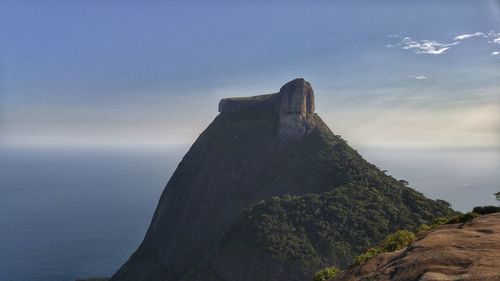 Scenic view of sea by cliff against sky