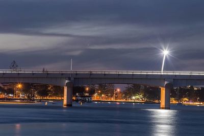 Illuminated bridge over street against sky at night