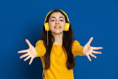 Portrait of smiling young woman against blue background