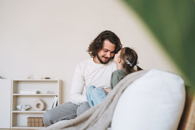 Young happy family with father and daughter on sofa in the cozy home, father day