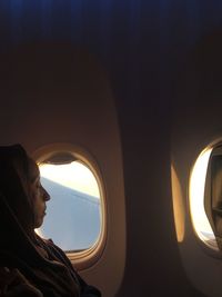 Side view of woman with eyes closed traveling by window in airplane