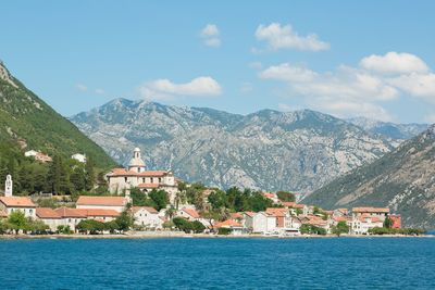 Houses by sea against mountains during sunny day