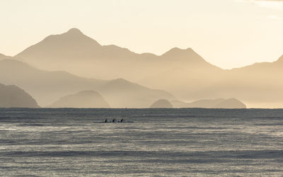 Scenic view of sea and silhouette mountains against clear sky