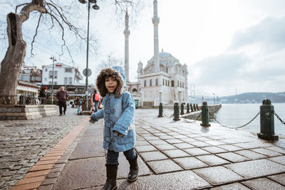 Portrait of young woman standing against building