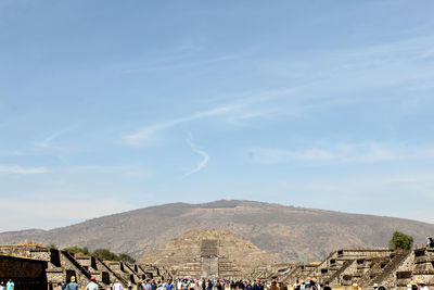 People walking on field against mountain