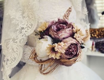 Midsection of bride holding bouquet at wedding ceremony