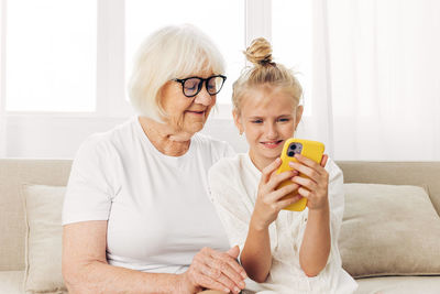 Young woman using mobile phone while sitting on sofa at home