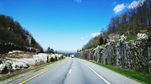 Empty road along trees and blue sky