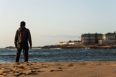 Rear view of man standing on beach against sky