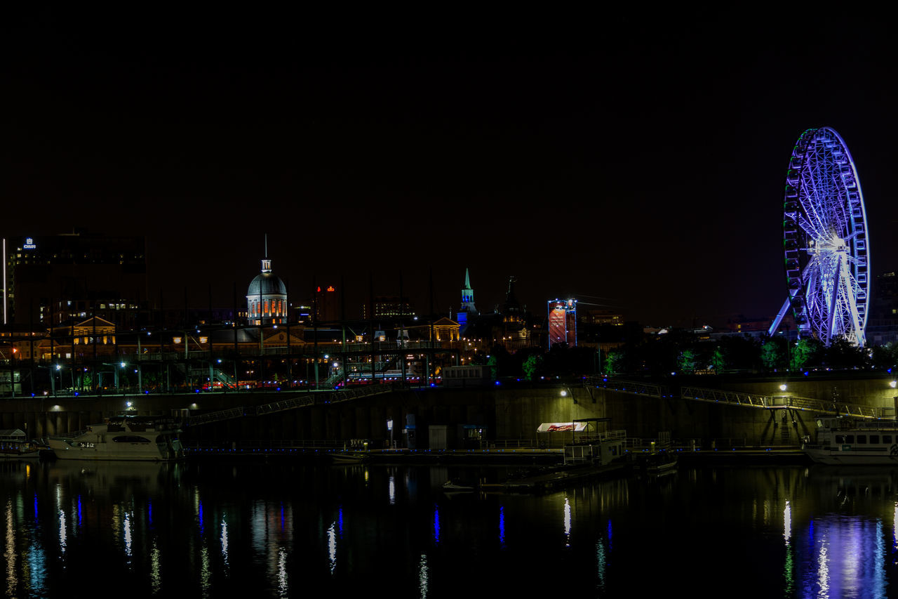 ILLUMINATED CITY BY RIVER AGAINST SKY