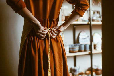 Woman's hands tying an apron, rear view person