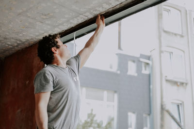 A young caucasian man repairing a window opening while and cleaning the frames with his hand