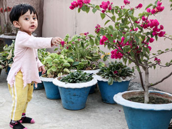 Full length of girl standing by potted plant