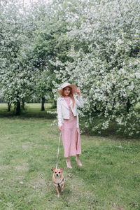 Woman holding umbrella while standing by tree