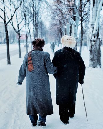 REAR VIEW OF WOMAN ON SNOW COVERED LAND