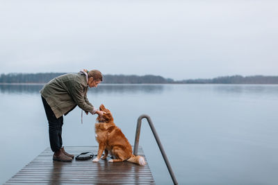 Girl staying on pier and looking in eyes of brown retriever. friendship between dog and woman.