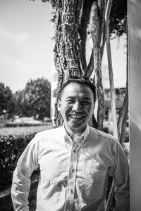 Portrait of smiling young man standing against trees