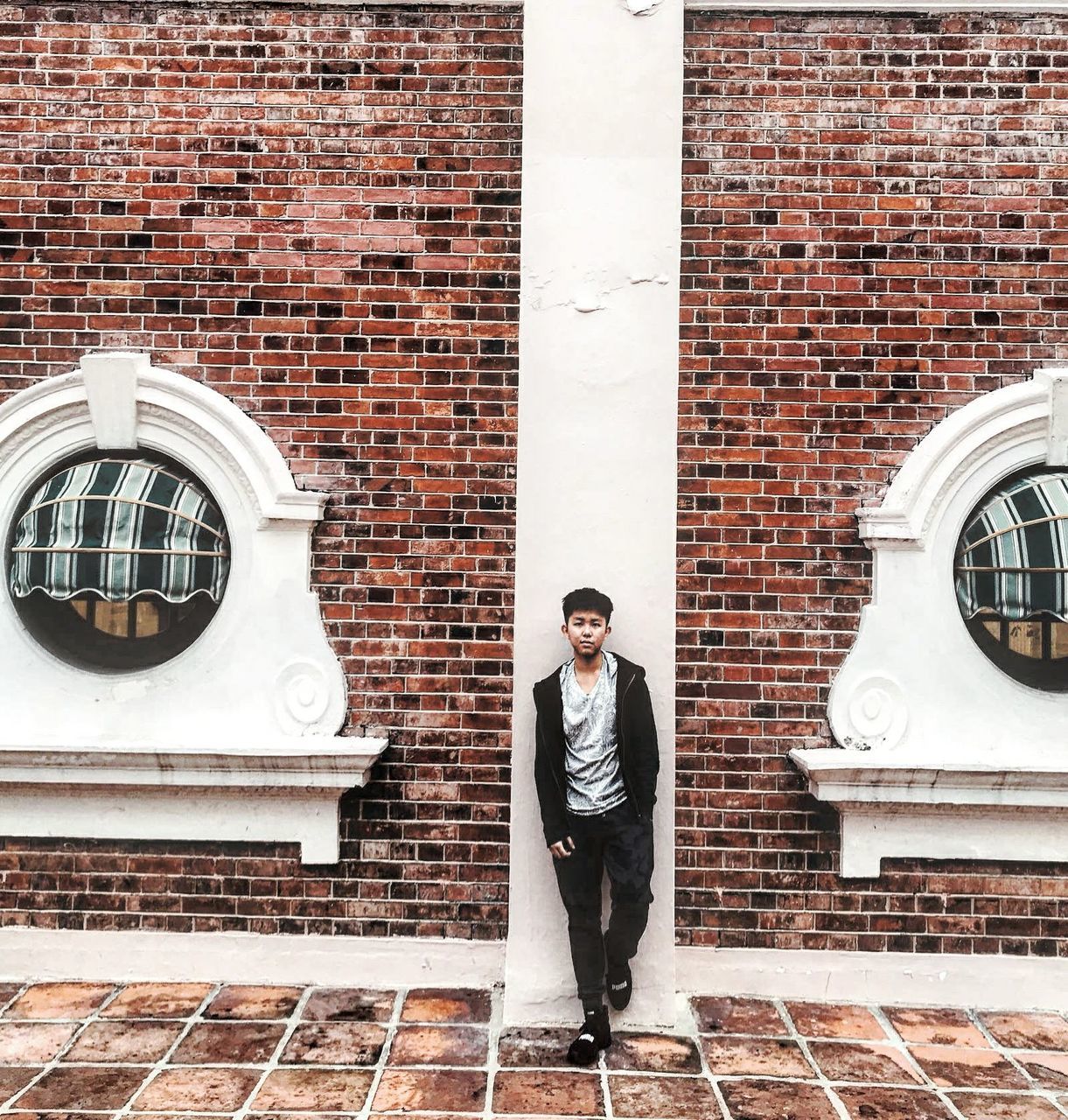 one person, real people, front view, young adult, standing, young men, architecture, building exterior, brick, brick wall, wall, portrait, lifestyles, full length, males, men, built structure, well-dressed, day, outdoors, menswear