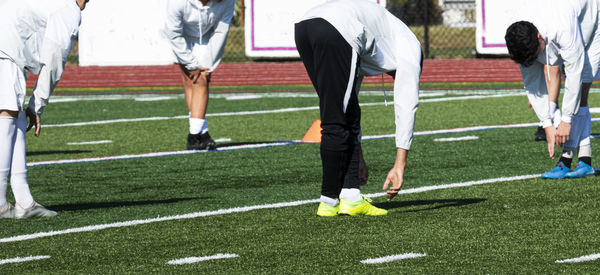 Low section of people playing soccer on field