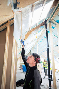 Side view of carpenter measuring height while working at site