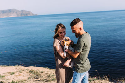 Happy couple with favourite pet. young man and woman have walk near sea.