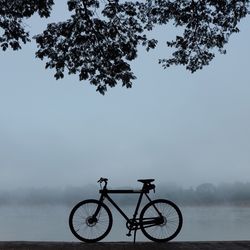 Bicycle at lakeshore against sky