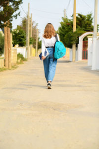 Rear view of girl walking on footpath in city