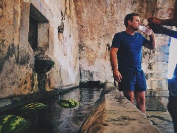 Man drinking water while standing by fountain