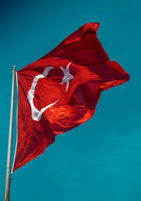 Low angle view of turkish flag against blue sky